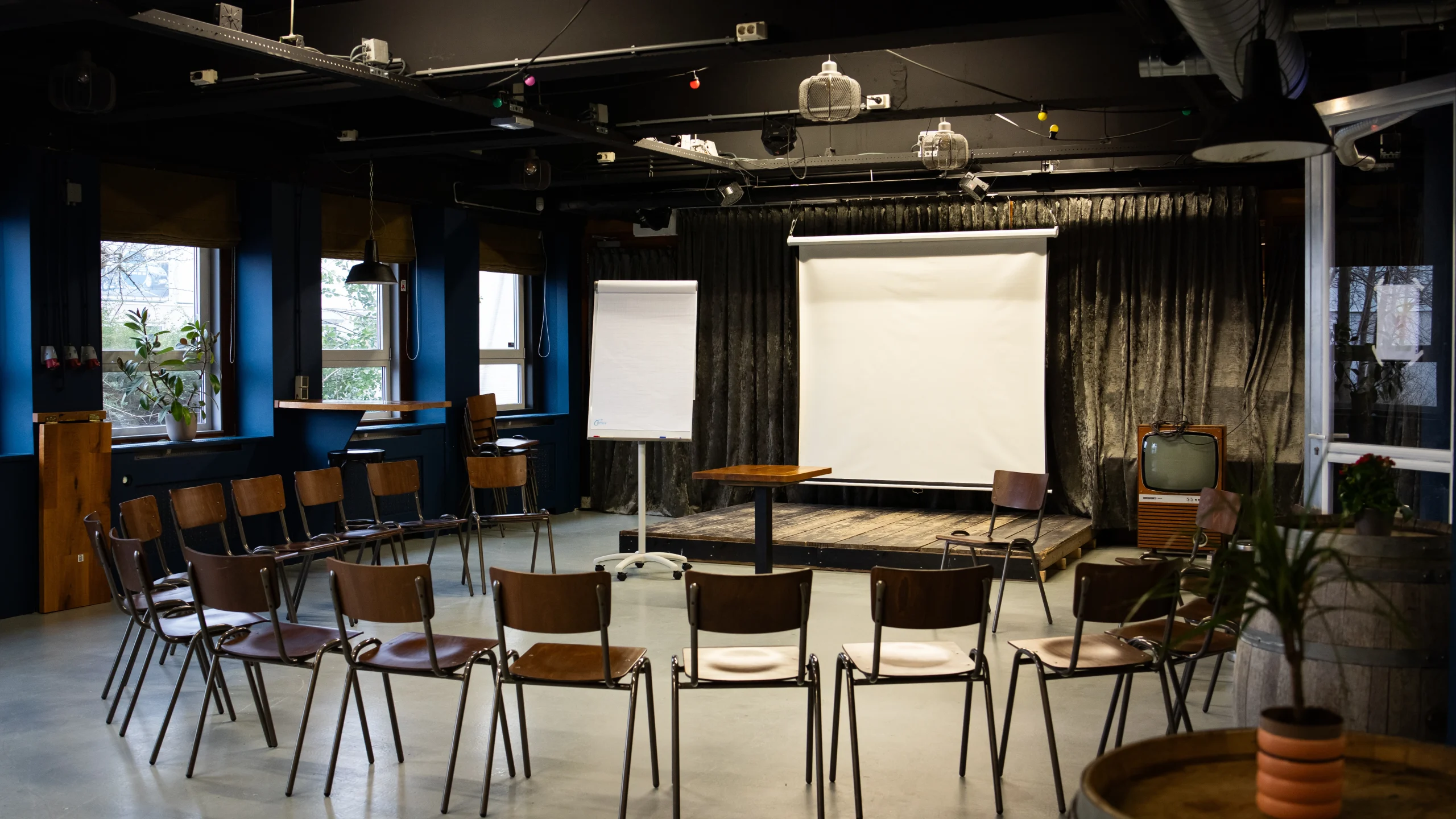 Een vergaderruimte met een projectiescherm en flip-over. Stoelen in een kring.